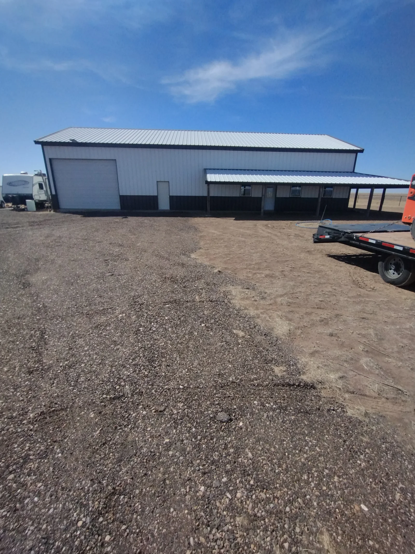 Standing seam metal roof on agricultural building with pitched design and attached covered structure