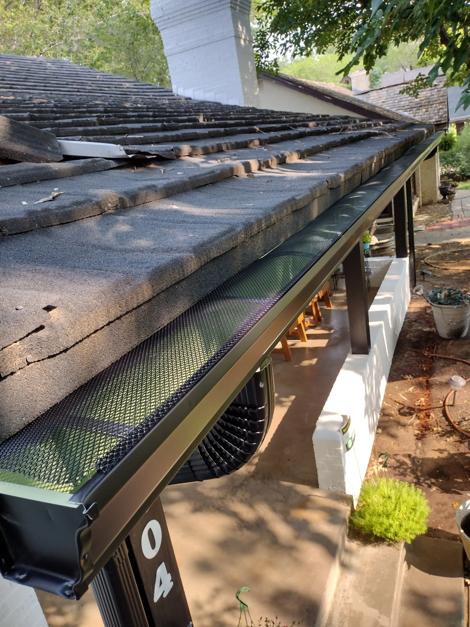 Roof decking exposed during tear-off with new gutter and mesh guard installed