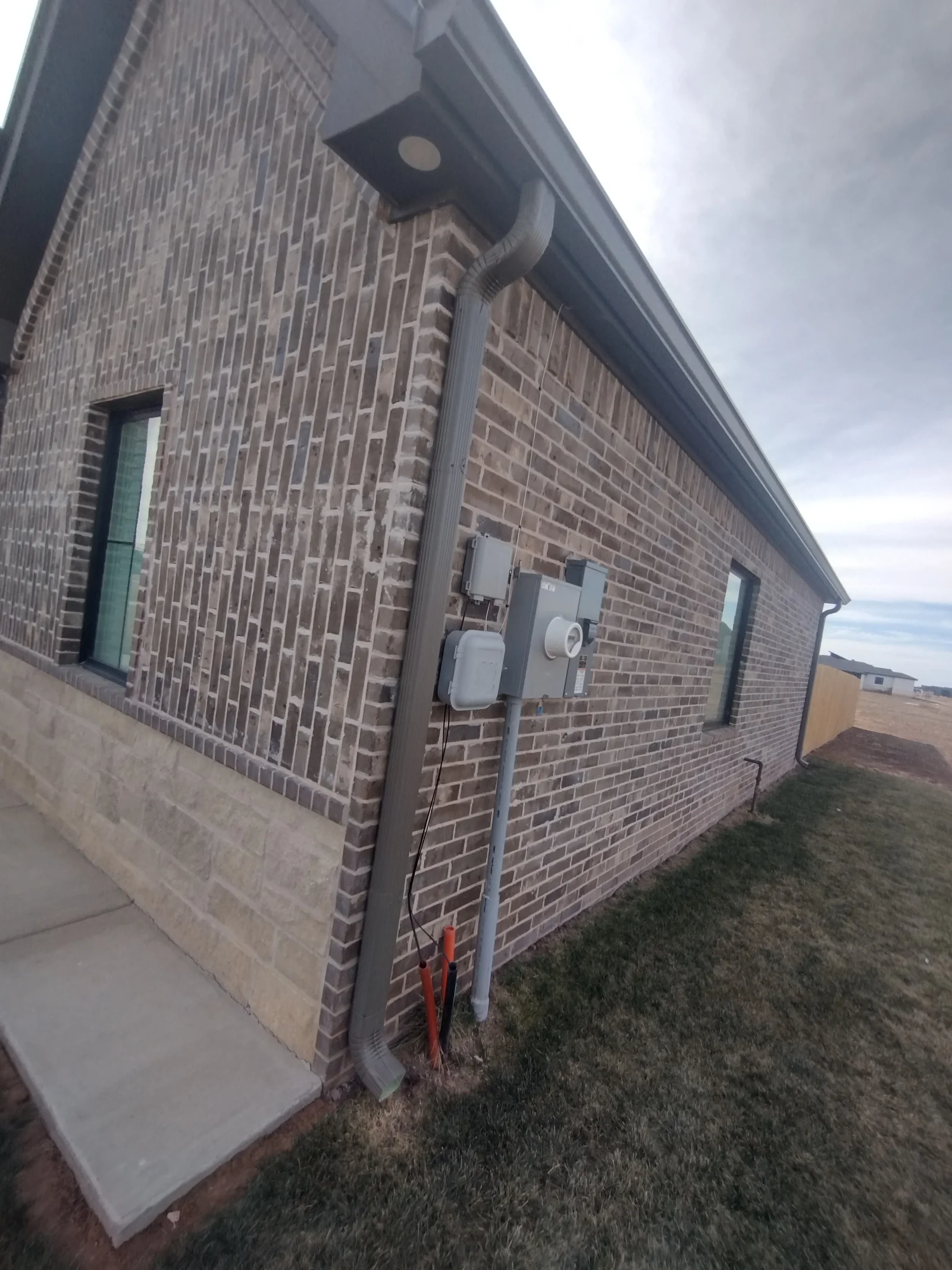 Brick home exterior with installed gutters, downspouts, and soffit vents