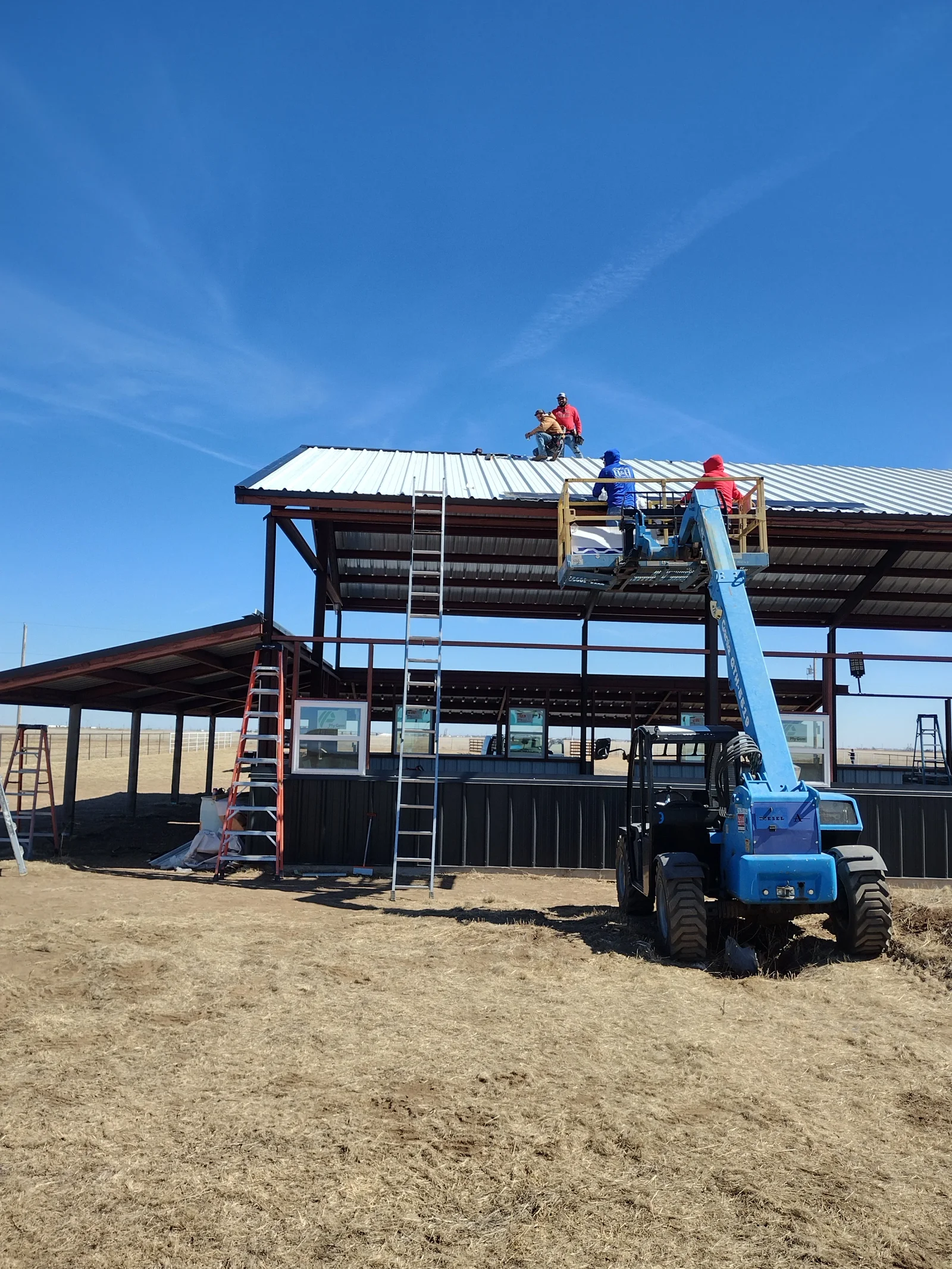 Metal roof installation on agricultural building using aerial lift and standing seam panels