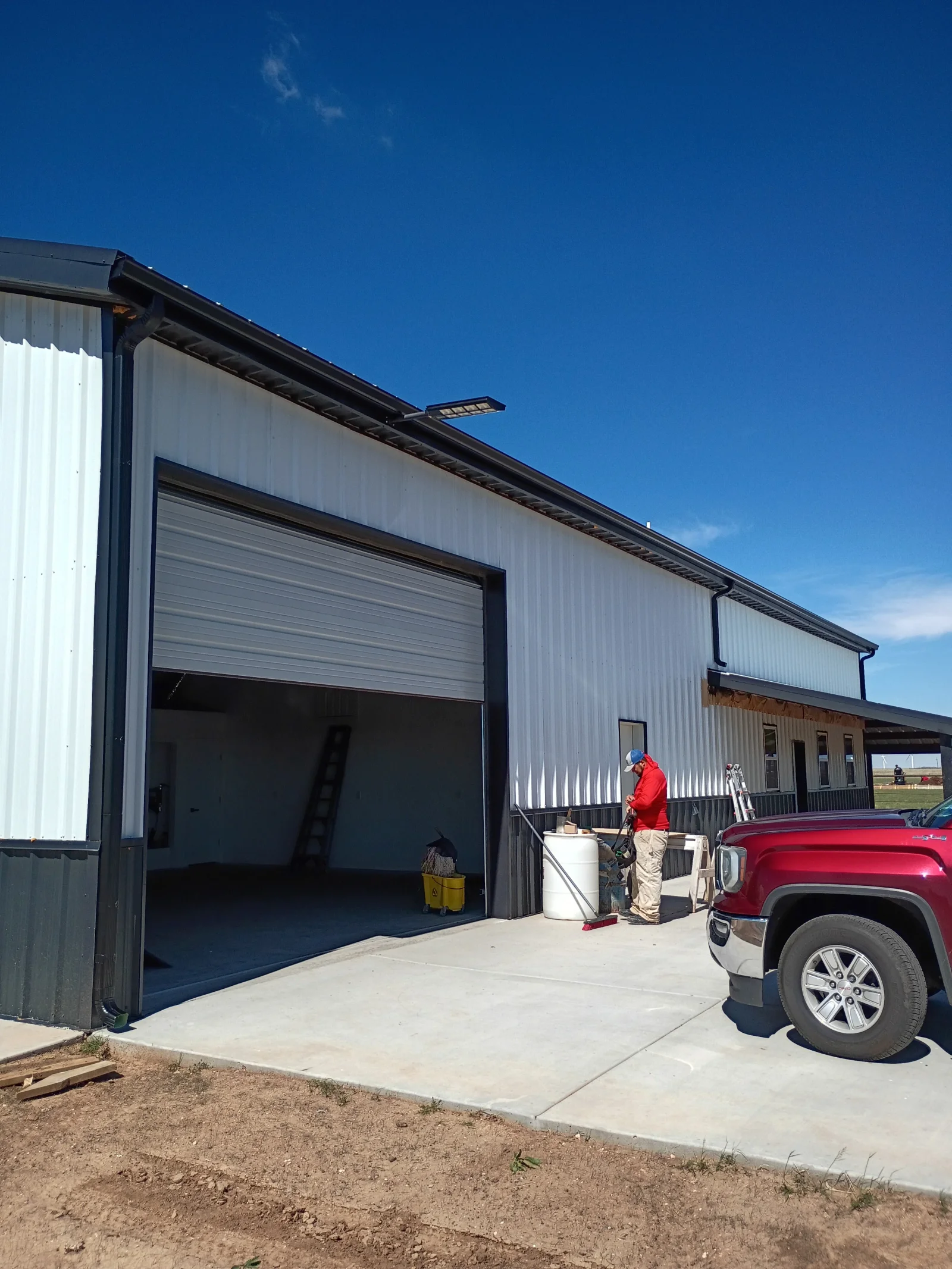Large metal garage door installed on white corrugated metal building with black trim and concrete apron