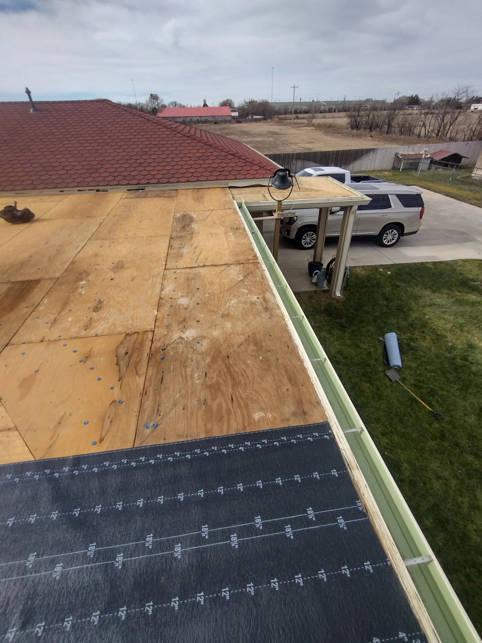 Burgundy architectural shingles, plywood decking, ice and water shield, and green gutter trim on pitched roof