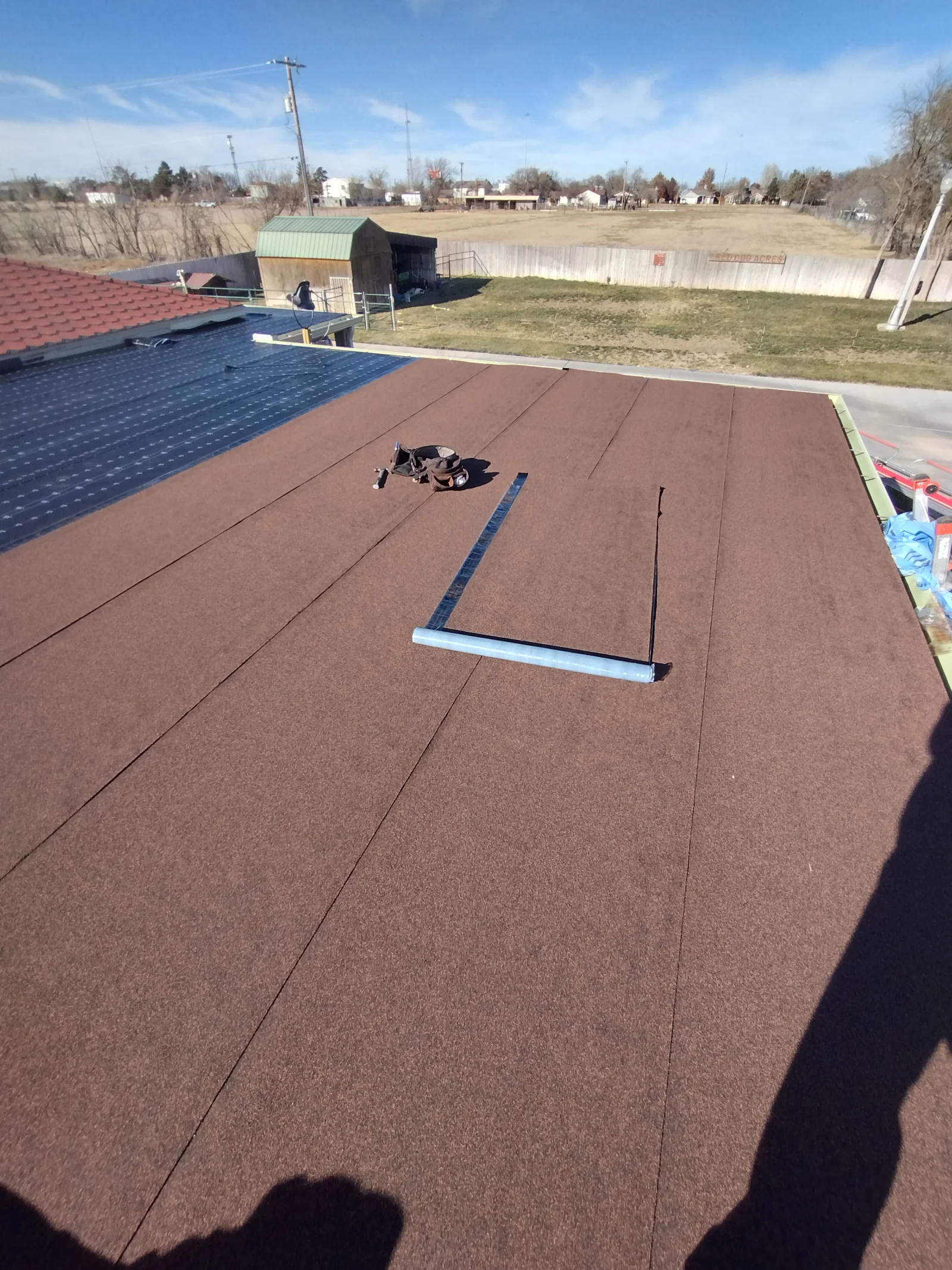 Burgundy asphalt shingles installed on pitched roof with metal flashing and seams