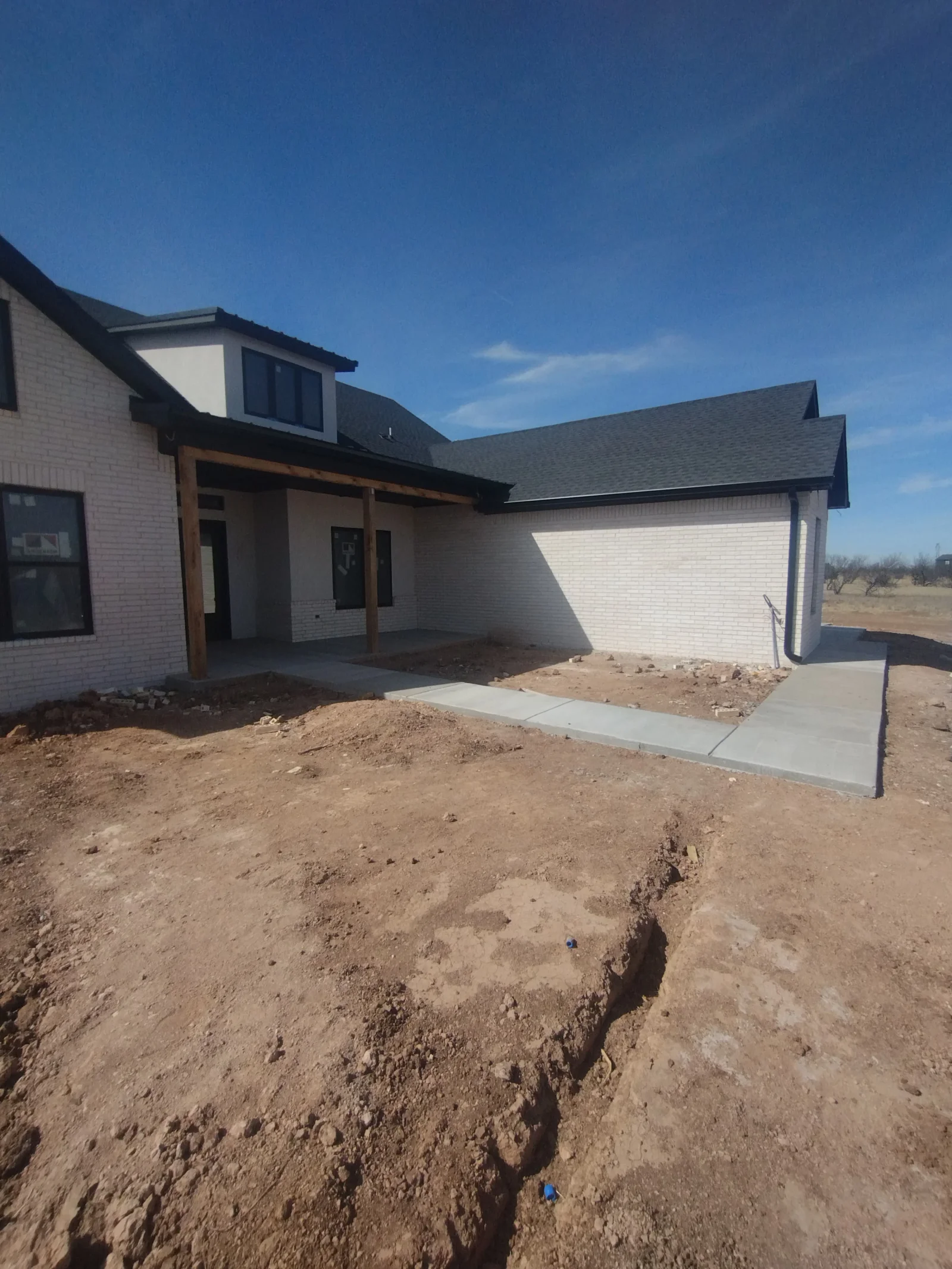 New white brick home with dark shingle roof installation, multiple peaks and dormers