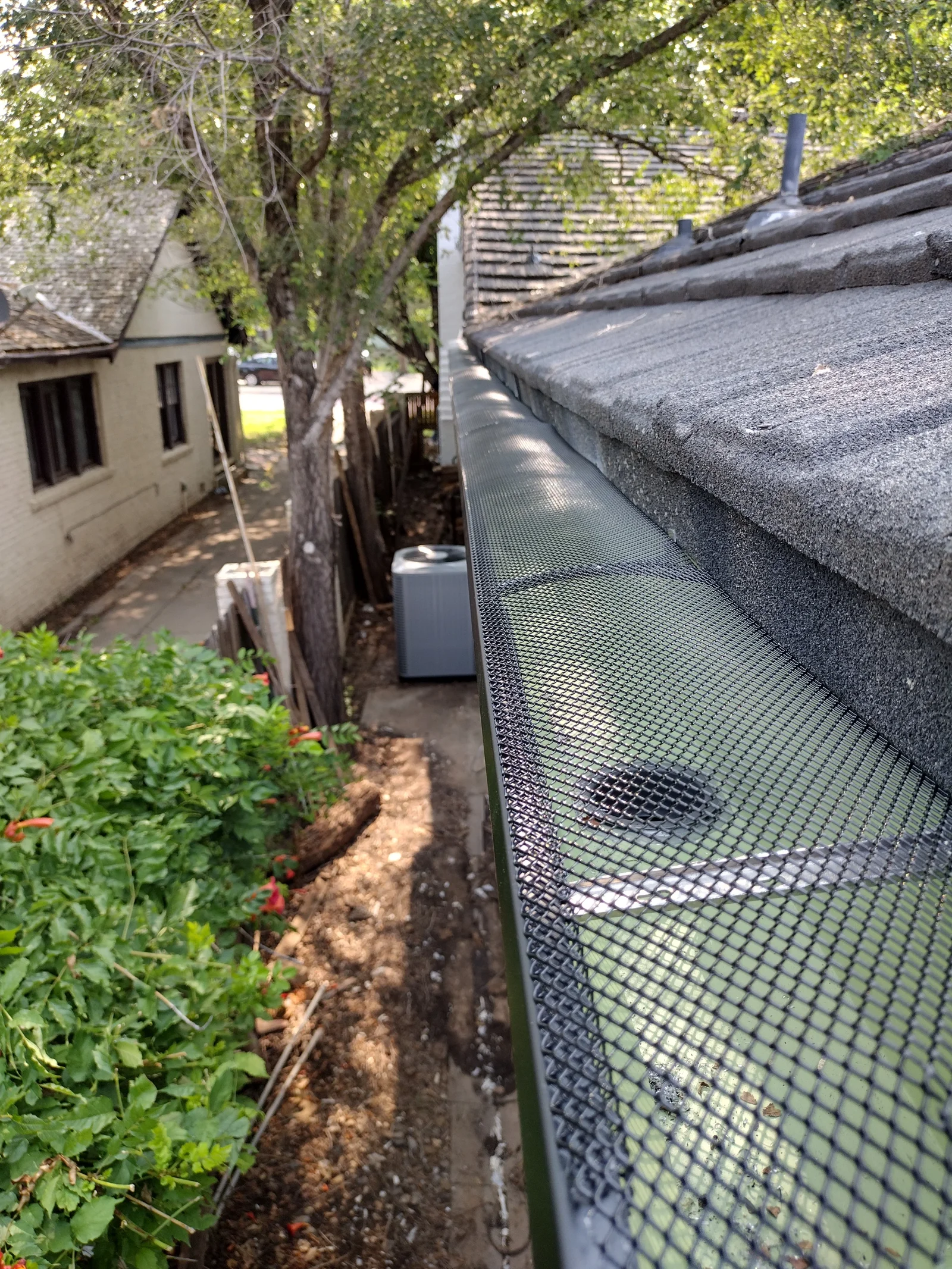 Metal mesh gutter guard installed on residential gutter with slate roof visible