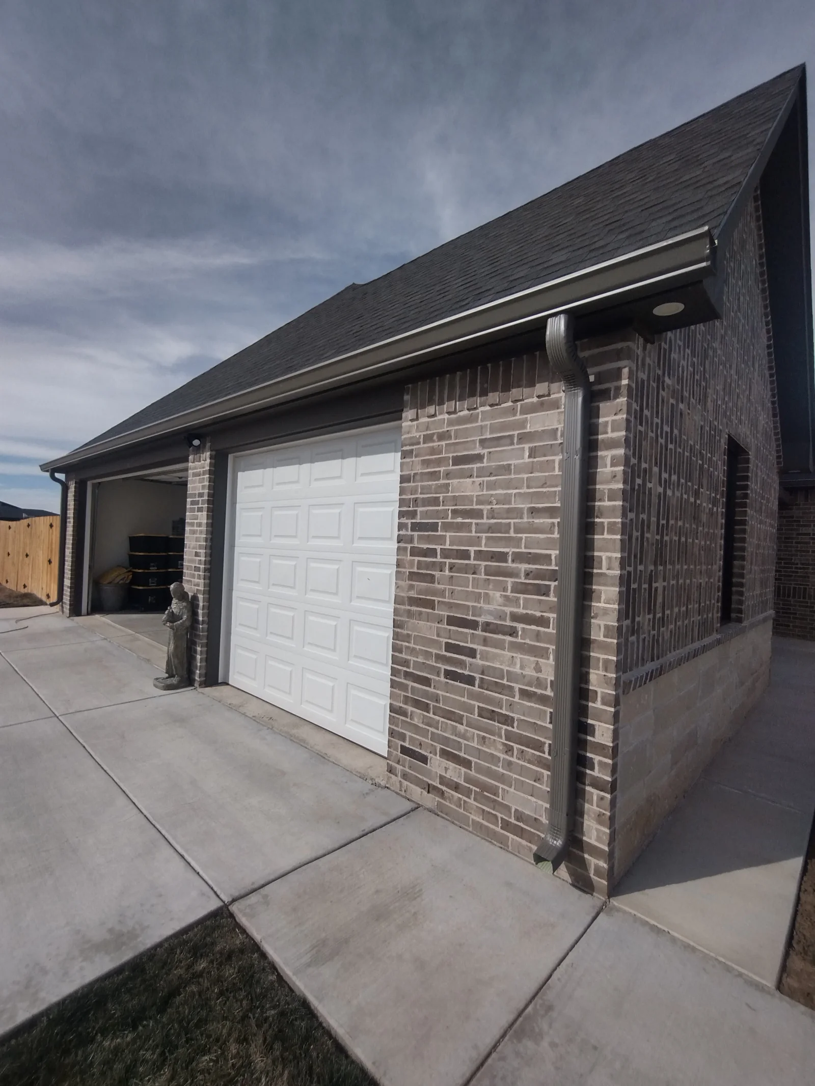 New charcoal asphalt shingle roof with fascia, soffit, and gutters on brick garage