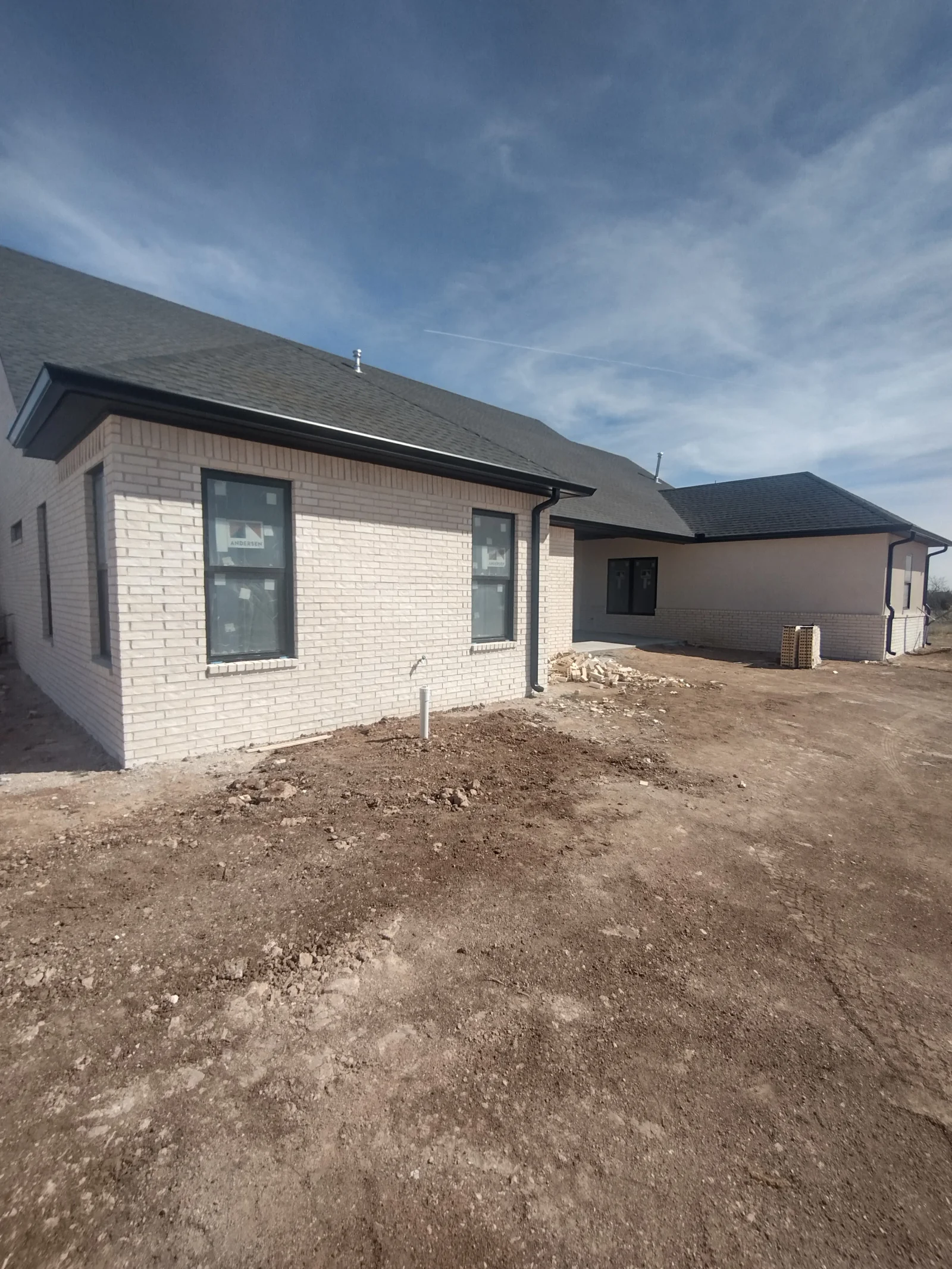 New asphalt shingle roof installation on brick residential home under construction