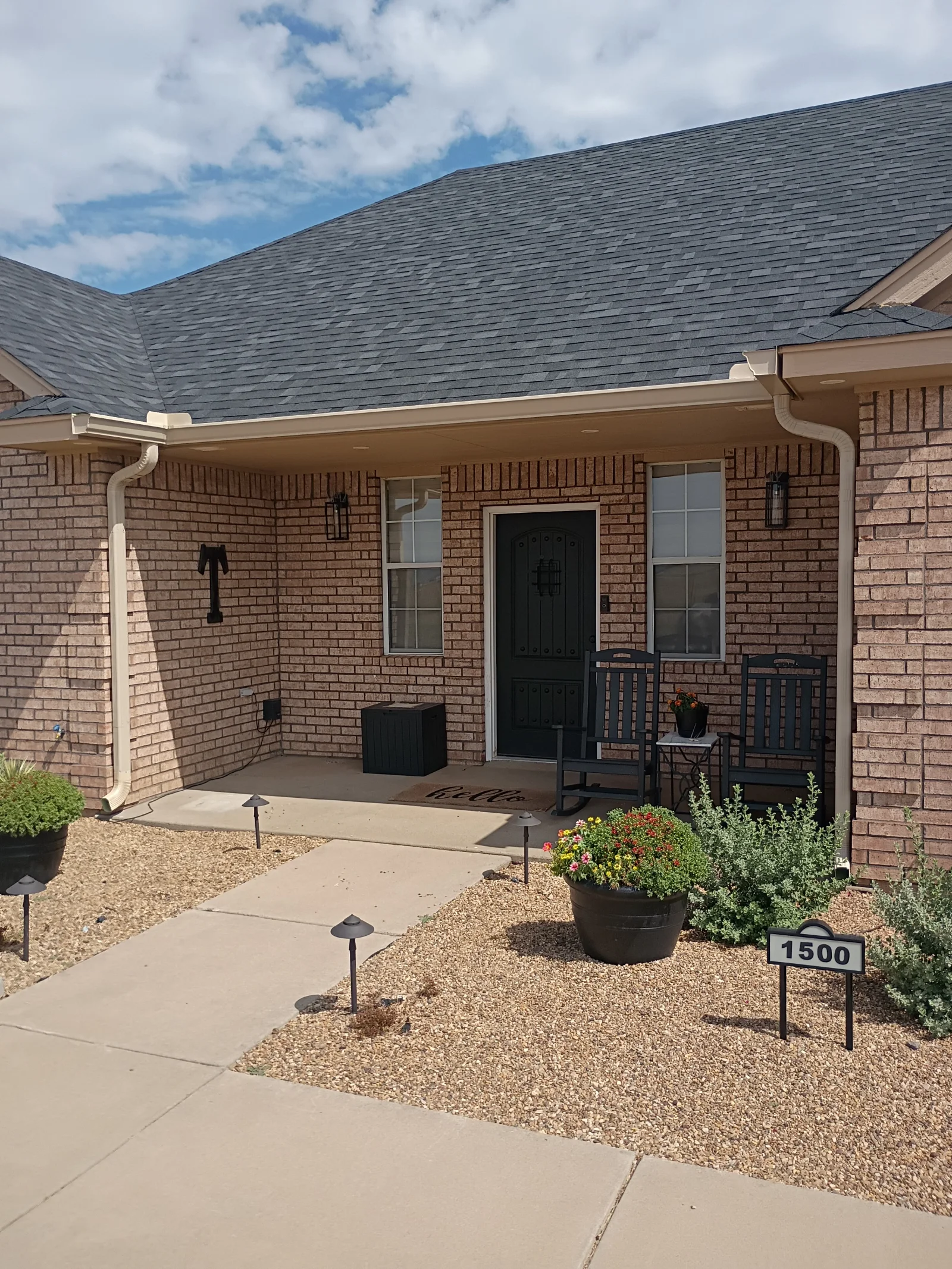 Charcoal gray architectural shingle roof with white gutters and downspouts on brick home