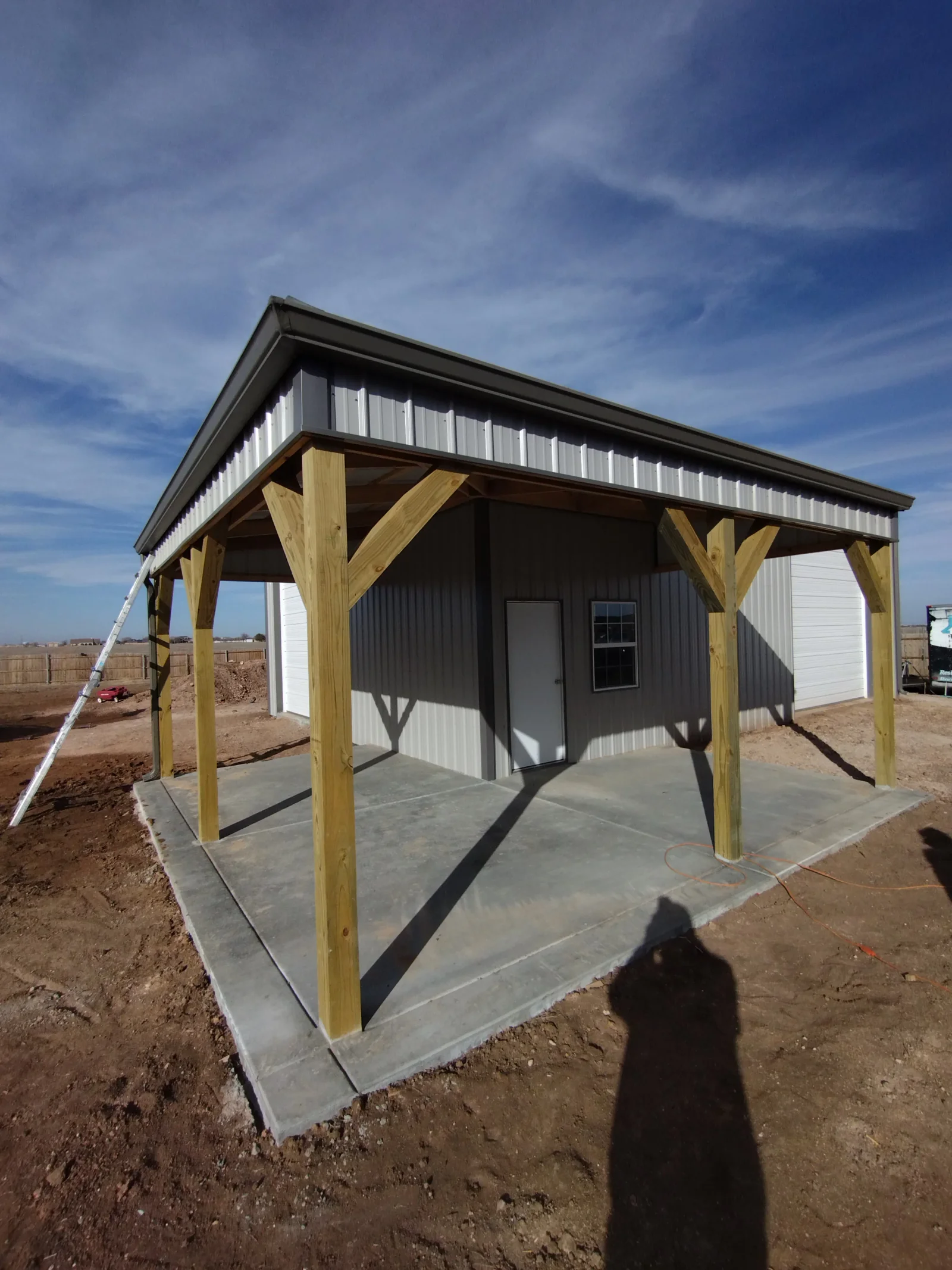 Metal roof with corrugated panels, timber posts, and concrete pad foundation on new porch structure