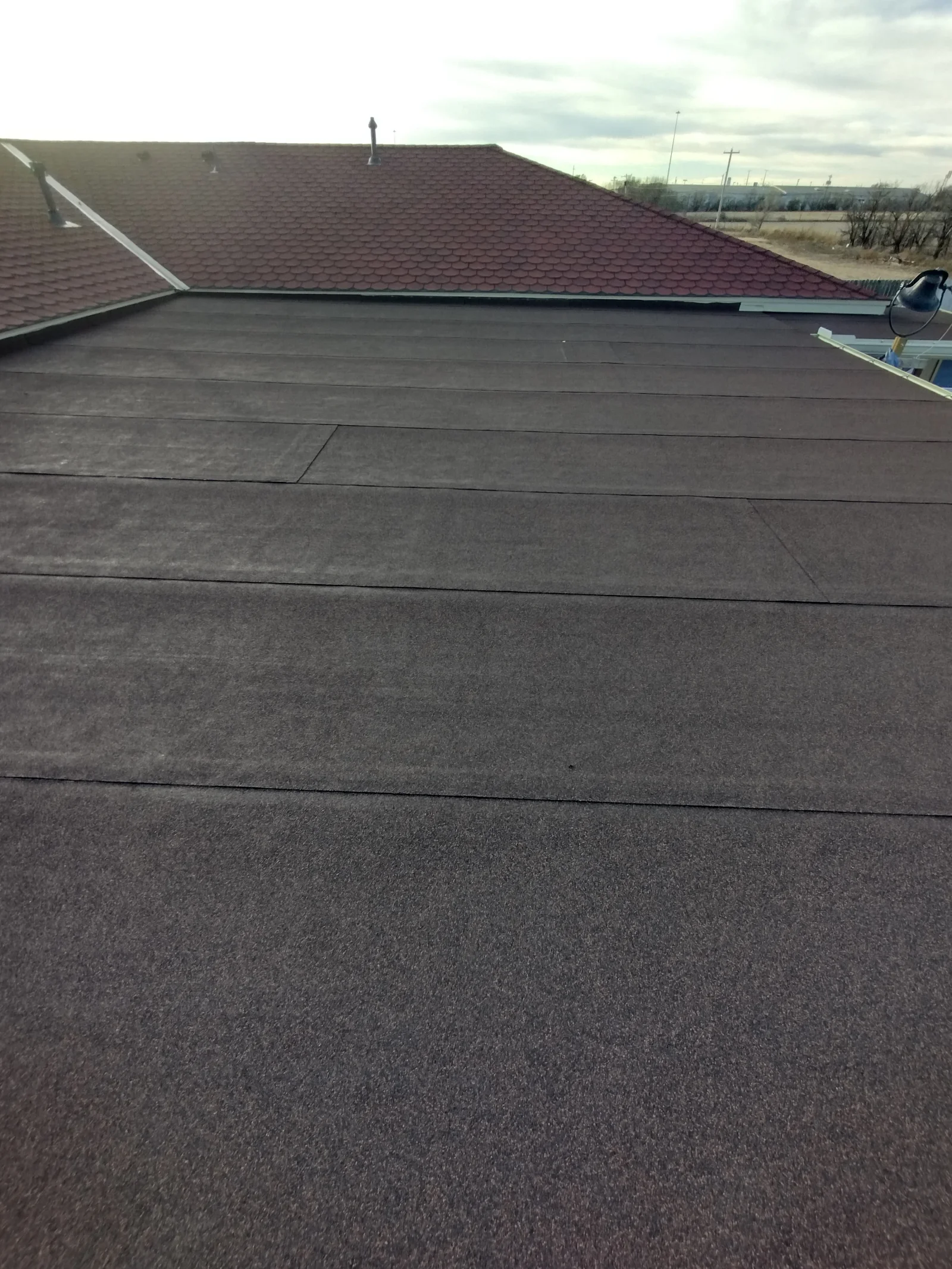 Dark gray flat roof membrane with seams and metal edge flashing installed